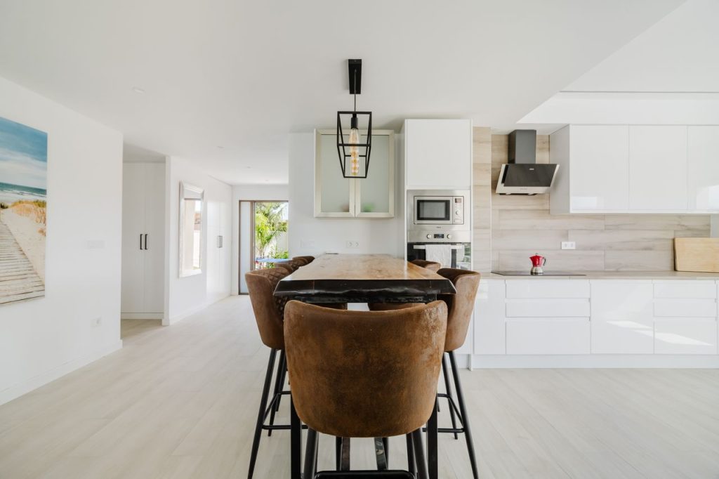 Bright and stylish modern Mediterranean kitchen featuring a central island and brown leather stools.
