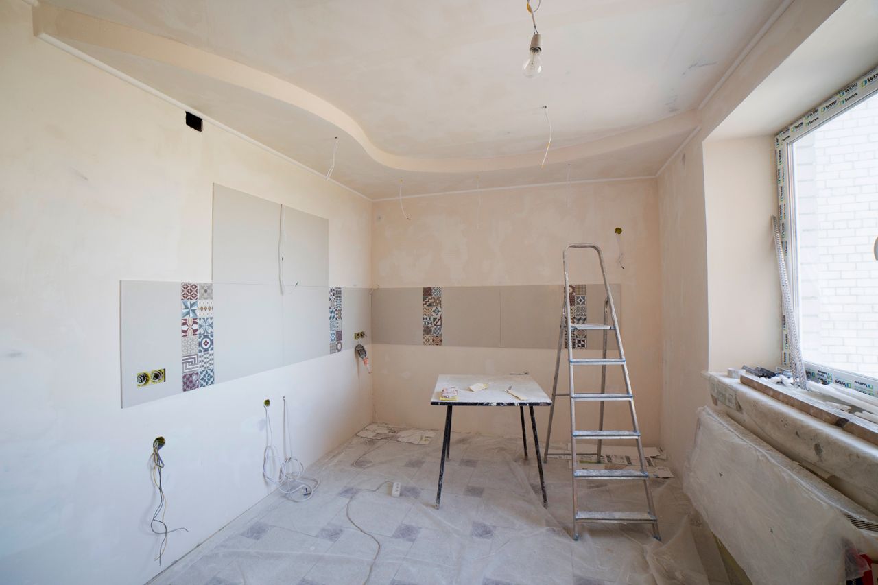 contact-img Spacious kitchen under renovation with ladder and tools, showcasing a fresh new design.
