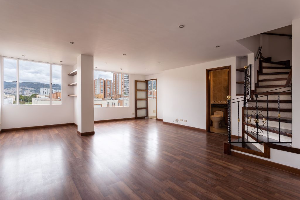 pexels photo 9826454 9826454 Bright empty living room with wooden floors, large windows, and a staircase.